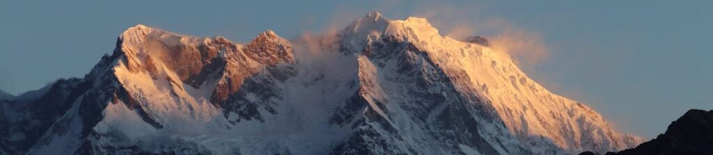 Majestic Himalayas at sunrise with snow-covered peaks glowing under a clear sky.