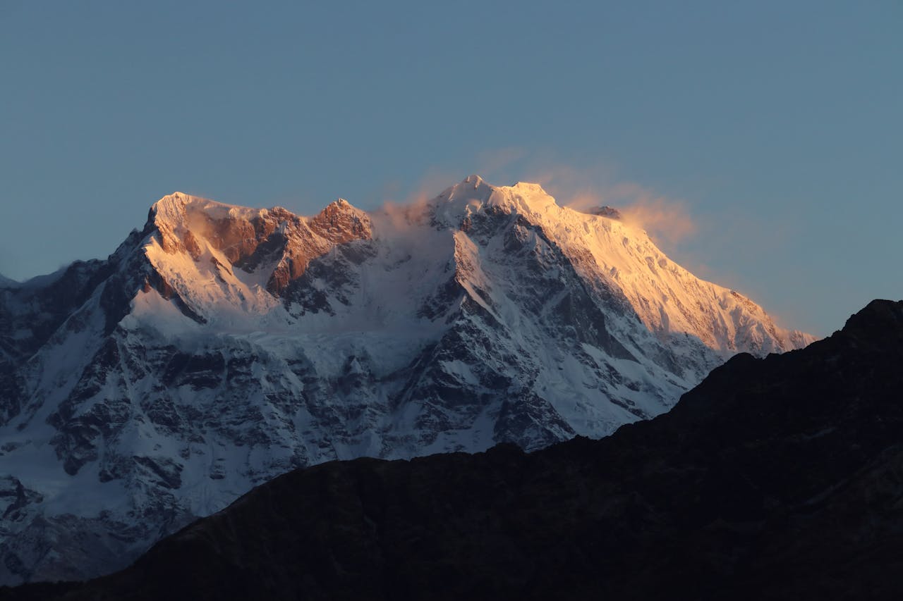 Majestic Himalayas at sunrise with snow-covered peaks glowing under a clear sky.